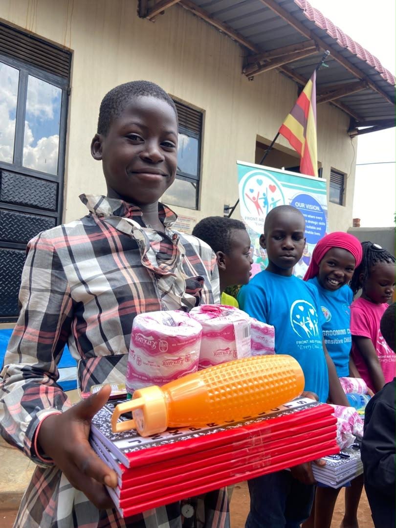 Children holding school supplies outside a building