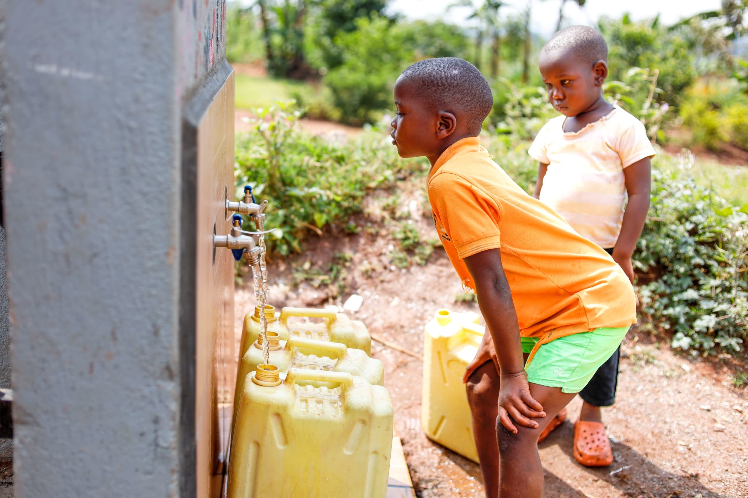 Children collecting water from outdoor taps in Buwambo